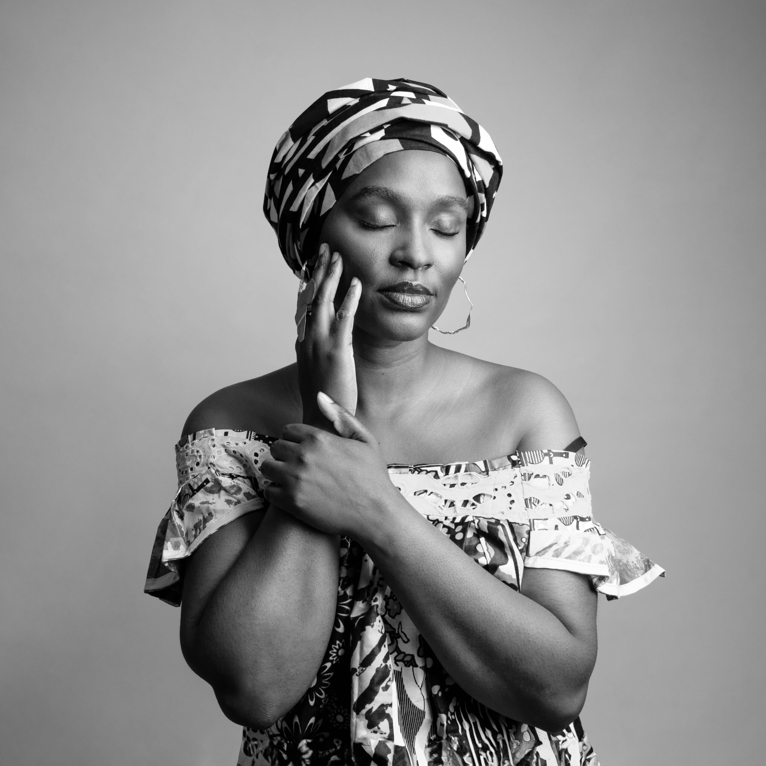 Fanny-D-photographe-portraitn-scaled Une femme posant les yeux fermés, avec un turban et une robe à motifs.